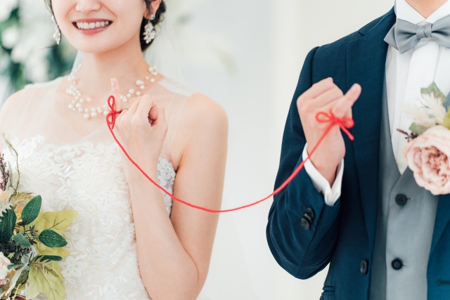 結婚式で小指を赤い糸で繋ぐカップル